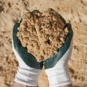 Hands with gardening gloves on holding White Sand